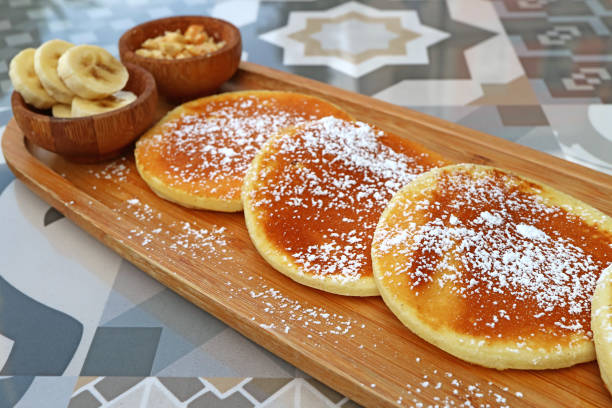 istock Pancakes with icing sugar on wooden plate served on patterned stone table 1387640104