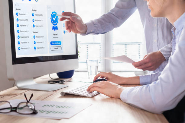 istock Quality Assurance (QA) and Control (QC) management. Standardization and certification concept. Compliance to international ISO standards. Manager and auditor looking at certificate on computer screen. 1387645293