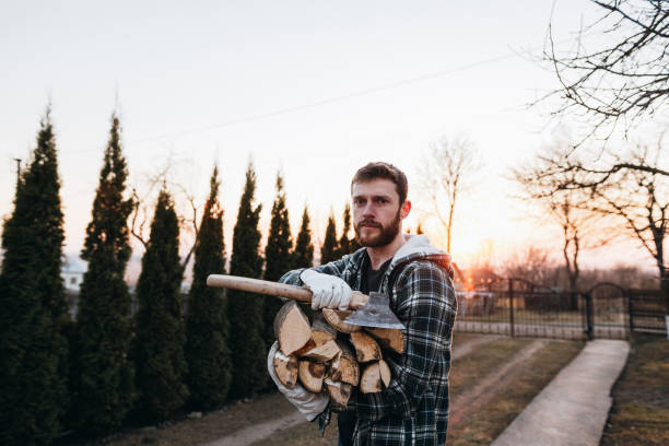 A man in work clothes is chopping wood for a bathhouse.