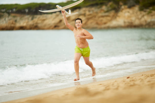 istock A boy runs with a toy plane by the water at the beach. 1387646378