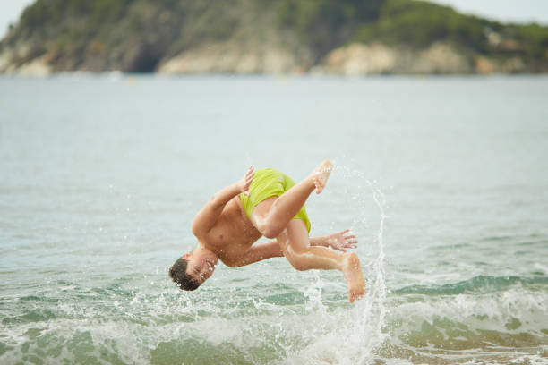 istock A boy does a backflip on the water's edge at the beach. 1387646420