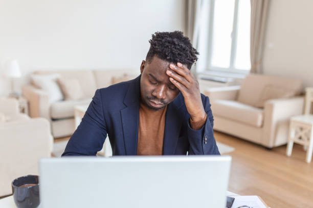 istock Stressed tired African American man touching temples, suffering from headache after long hours work, overworked overwhelmed businessman sitting at desk, feeling unwell 1387649597