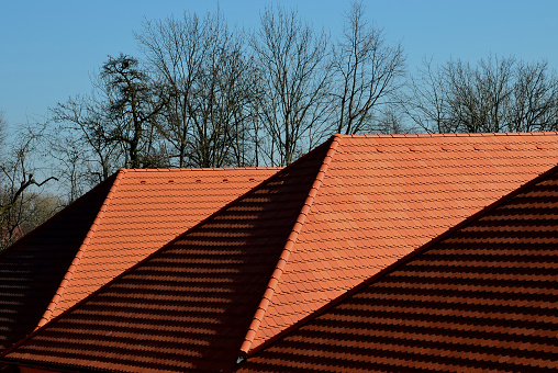 view of the roof made of red brick burnt tiles of the beaver type used in Central Europe on all historical roofs, especially in Austria. the bags overlap several times, they look like beaver teeth