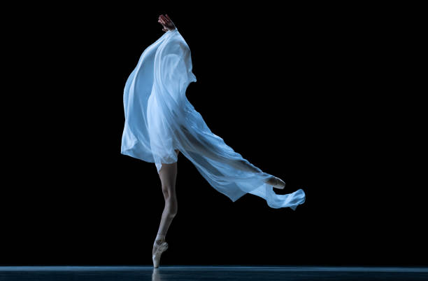 Graceful classic ballerina dancing with weightless cloth isolated on black studio background. Theater, art, beauty, grace, action and motion, ad concept. Artist of ballet in solo performance
