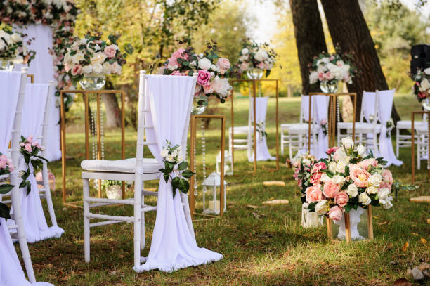 Preparation for a wedding ceremony outdoor Preparation for a wedding ceremony outdoor in the park/ forest . Wood arch and chairs are decorated with white and pink flowers roses and peony, on the ground are many wood lanterns with candles. pink memorial candle with flowers stock pictures, royalty-free photos & images