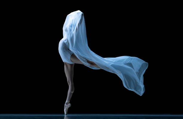 istock Graceful classic ballerina dancing with weightless fabric isolated on black studio background in neon. Theater, art, beauty, grace, action and motion concept. 1387651555