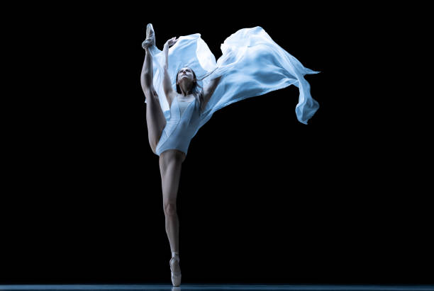 istock Graceful classic ballerina dancing with weightless fabric isolated on black studio background in neon. Theater, art, beauty, grace, action and motion concept. 1387651566