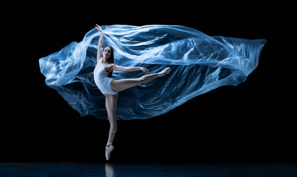 istock Graceful classic ballerina dancing with weightless fabric isolated on black studio background in neon. Theater, art, beauty, grace, action and motion concept. 1387651579