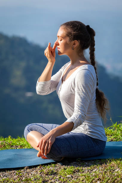 женщина практике пранаяма в позе лотоса на свежем воздухе - zen like nature breathing exercise sitting стоковые фото и изображения