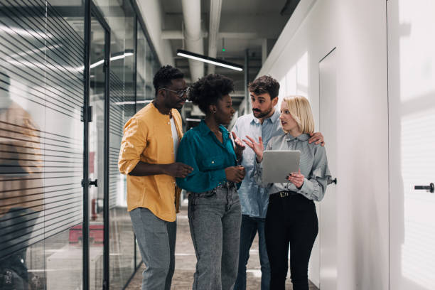 istock Group of startup employees walking together in office hallway 1387653417
