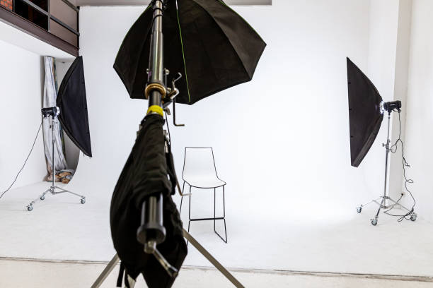 istock Empty photo studio with lighting equipment. Photographer workplace interior with professional tool set gear. Flash light white background scenes ready for studio shooting. Modern photographer studio 1387654996