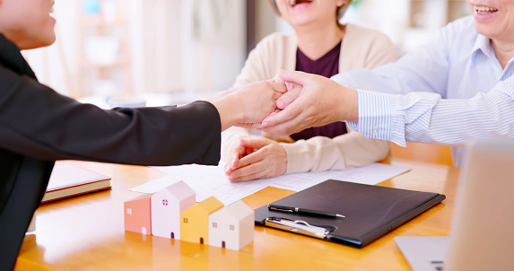 Authentic close up shot of elderly asian couple are buying house with real estate agent and make a deal then they shake hands