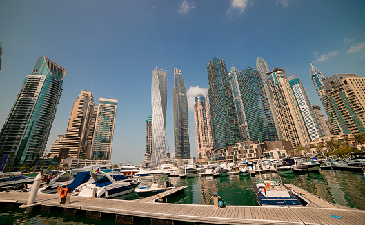 Dubai, UAE - November 06, 2021: Luxury Dubai Marina skyscrapers, cruise boat and promenade in beautiful sunny morning, United Arab Emirates