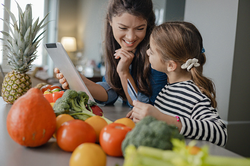 A young mother and her daughter using digital tablet for online shopping