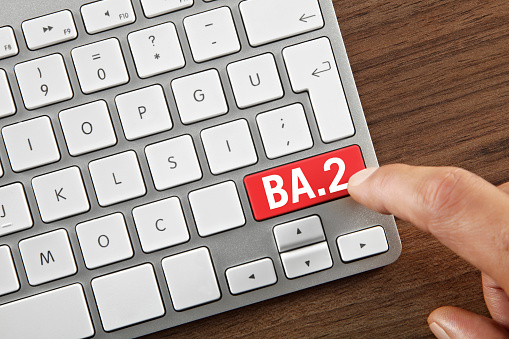 Man pushing BA.2 Omicron variant key on computer keyboard.