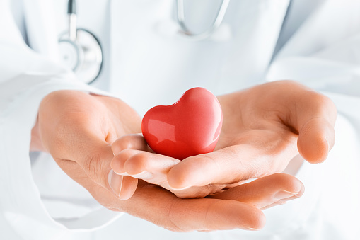 Doctor de manos sosteniendo el corazón rojo. Cardiología, salud cardíaca y atención. photo