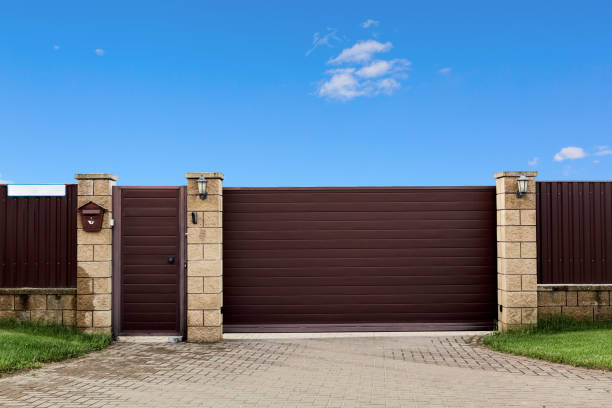 istock Brown metal profile fence with block posts. Entry group with gate, flashlight and postbox. Opaque surface, horizontal lines. Security. Private property fencing. Exterior. Pavement tiles on parking 1387665549