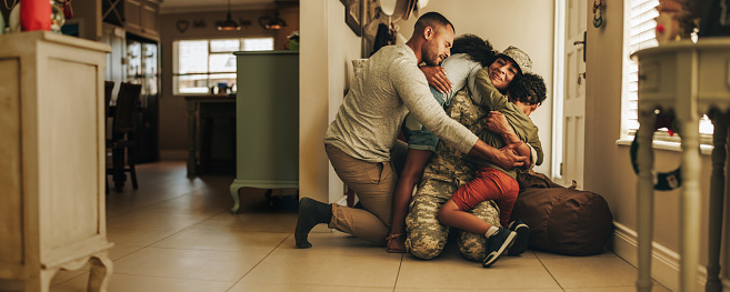 Much-awaited military homecoming. Female soldier reuniting with her husband and children after serving in the army. Cheerful servicewoman embracing her family after returning home from deployment.