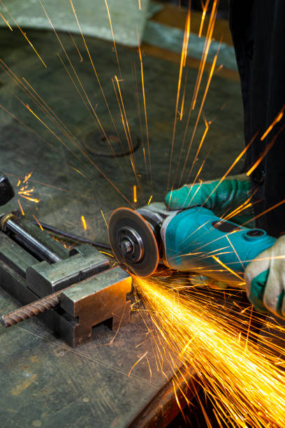 istock Metal Machining Concepts. Professional Fitter in Protective Gloves and Uniform Using Gringer Tool For Metal Work With Bunch of Sparks in Workshop. 1387668881