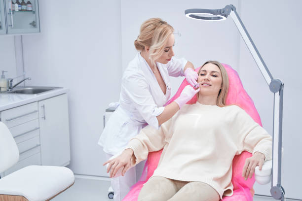 istock Experienced dermatologist reducing smile lines on woman face 1387668970