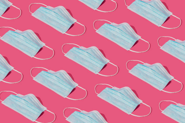 istock Pattern made with Coronavirus prevention medical surgical masks for corona virus protection. Global pandemic concept background. Trendy pink background. 1387669340
