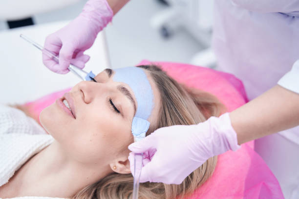 istock Beautician applying mask to patient face with brushes 1387669585