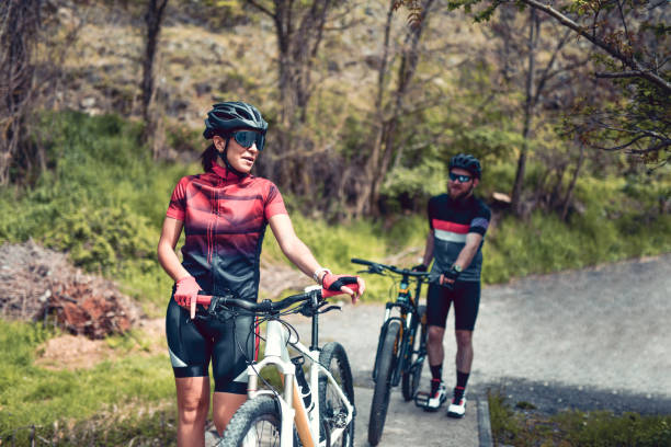 istock Cute Cyclist Couple Pushing Bicycles Across River Bridge 1387670639