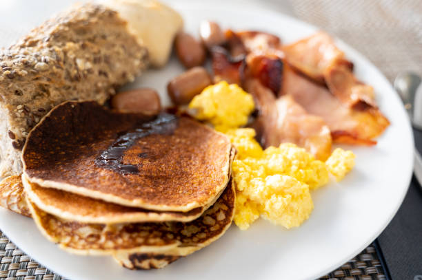 istock Close-up plate with English breakfast. Pancakes, eggs, sausages and bread. 1387672099