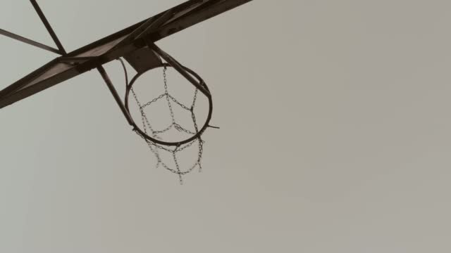 Basketball passing through a basketball hoop outdoors
