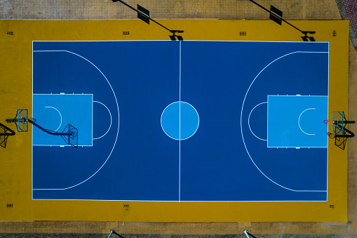 Aerial view of a tennis player during a match. Drone shot from behind a player, aerial view. Orange tennis court field.