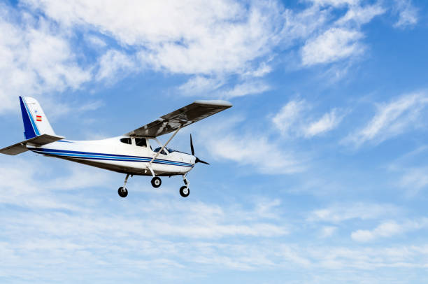 leichtflugzeug fliegt über blauem himmel - propellerflugzeug stock-fotos und bilder