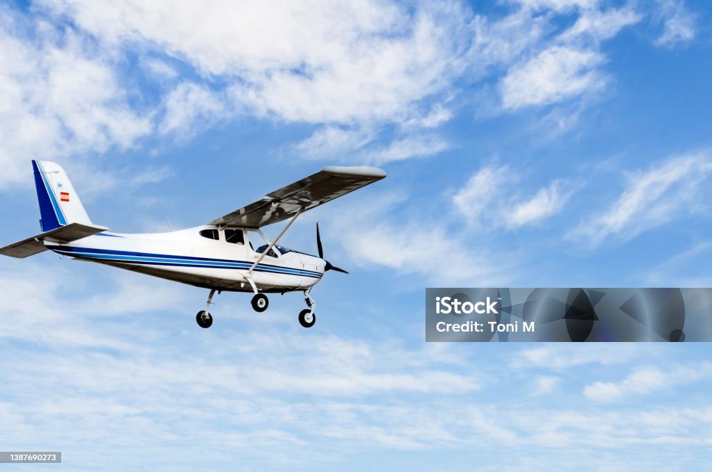 Light aircraft flying over blue sky Single engine ultralight plane flying in the blue sky with white clouds Propeller Airplane Stock Photo