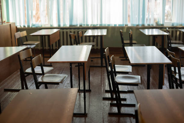 istock Desks for students at school. Classroom is empty. Chairs and tables are in row. 1387695509
