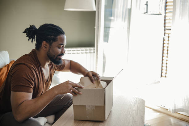 istock Smiling man opening his online delivery box 1387696140