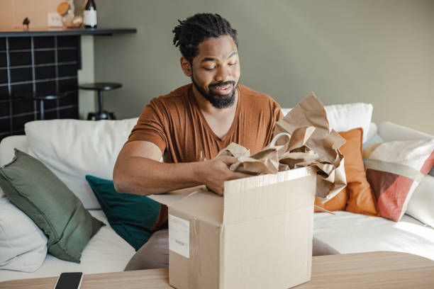 istock Young man unpacking the package he ordered online 1387697087