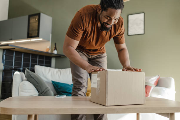 istock Young man unpacking the box in which his online order has arrived 1387697091