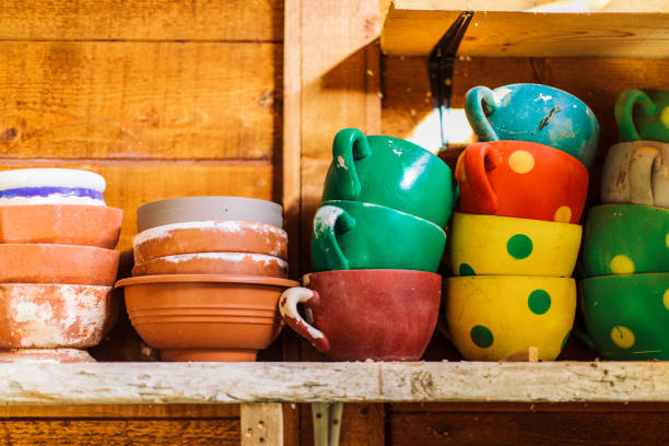 Storage of stack of used empty flower pots on shelf . Some of them are in shape of cup