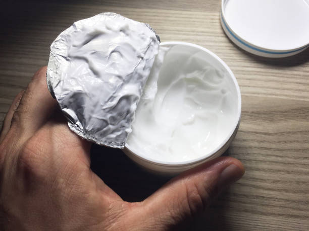 istock Hand holding open moisturizer cream on the wood background 1387699243