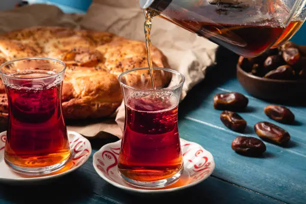 Turkish Ramazan concept with pita, tea and date, over blue background with copy space.