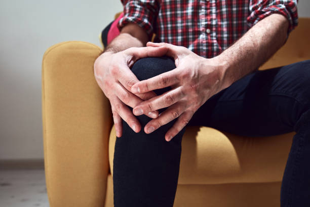 istock Man with injured knee at home. 1387705233