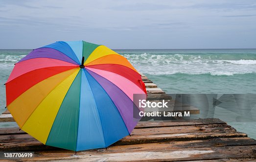 istock Colorful umbrella on wooden pier 1387706919
