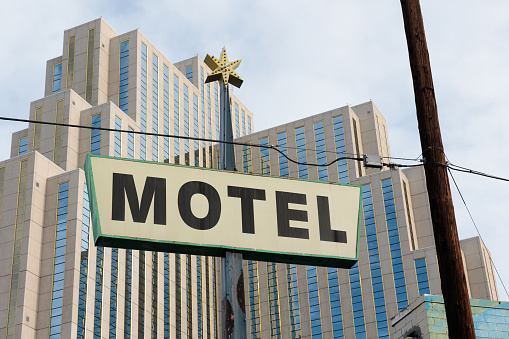 A vintage motel sign in front of a large, modern hotel