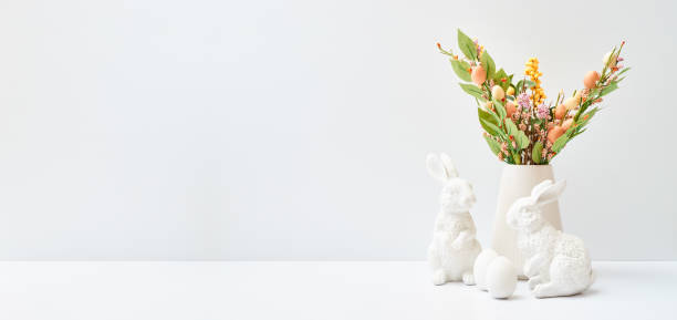 Easter decor in a vase, bunnies and eggs on a white table. Easter background with copy space