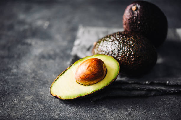 Close-up of fresh ripe raw hass avocados on black counter Close-up of fresh ripe raw hass avocados on black counter.  Healthy omega 3 vegan food. avocado brown stock pictures, royalty-free photos & images