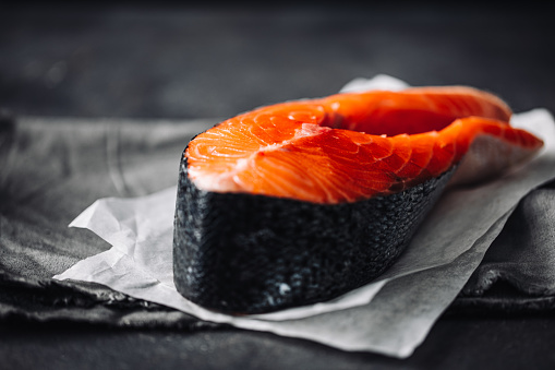 Close-up of a raw salmon steak on butter paper. Slice of raw salmon on kitchen counter.