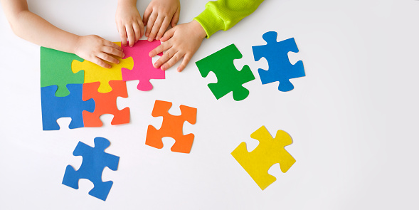 The pieces of multicolored puzzles are put together by children. The concept of supporting children with autism spectrum disorder. World Autism Awareness Day. Banner with copy space