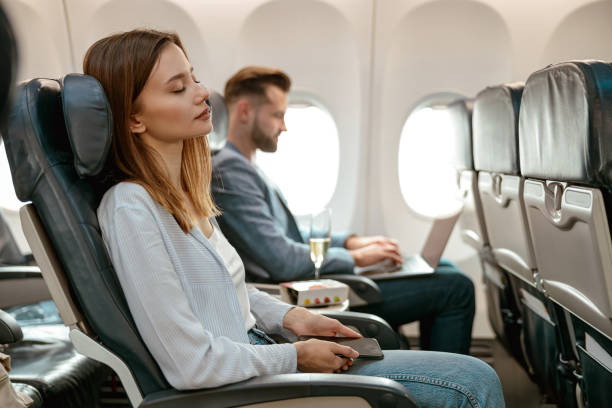 Young woman with cellphone resting in airplane stock photo