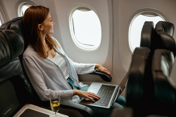 istock Female traveler using laptop in passenger plane 1387722704