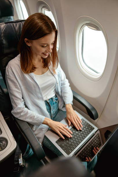 istock Joyful woman working on laptop in airplane 1387722711