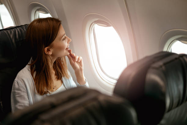 istock Cheerful woman looking out the window in airplane 1387722713